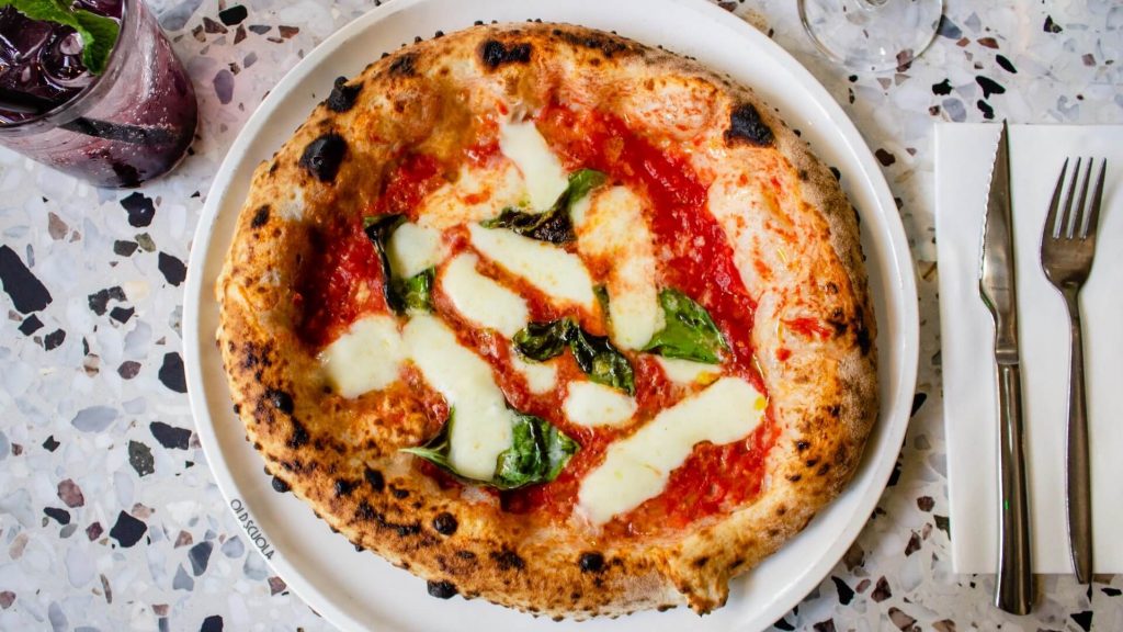Un'appetitosa Pizza Margherita, condita con pomodoro, mozzarella, basilico e olio d'oliva, che rappresenta la tradizione culinaria italiana